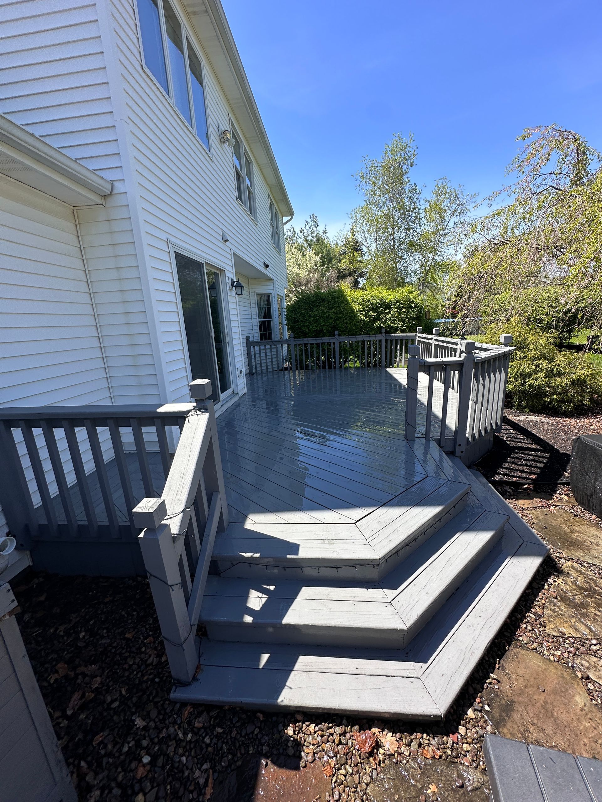 A large white house with a large deck and stairs leading up to it.
