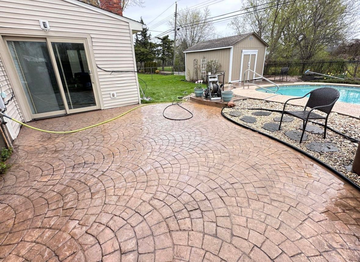 A patio with a chair and a hose in front of a house and a pool.