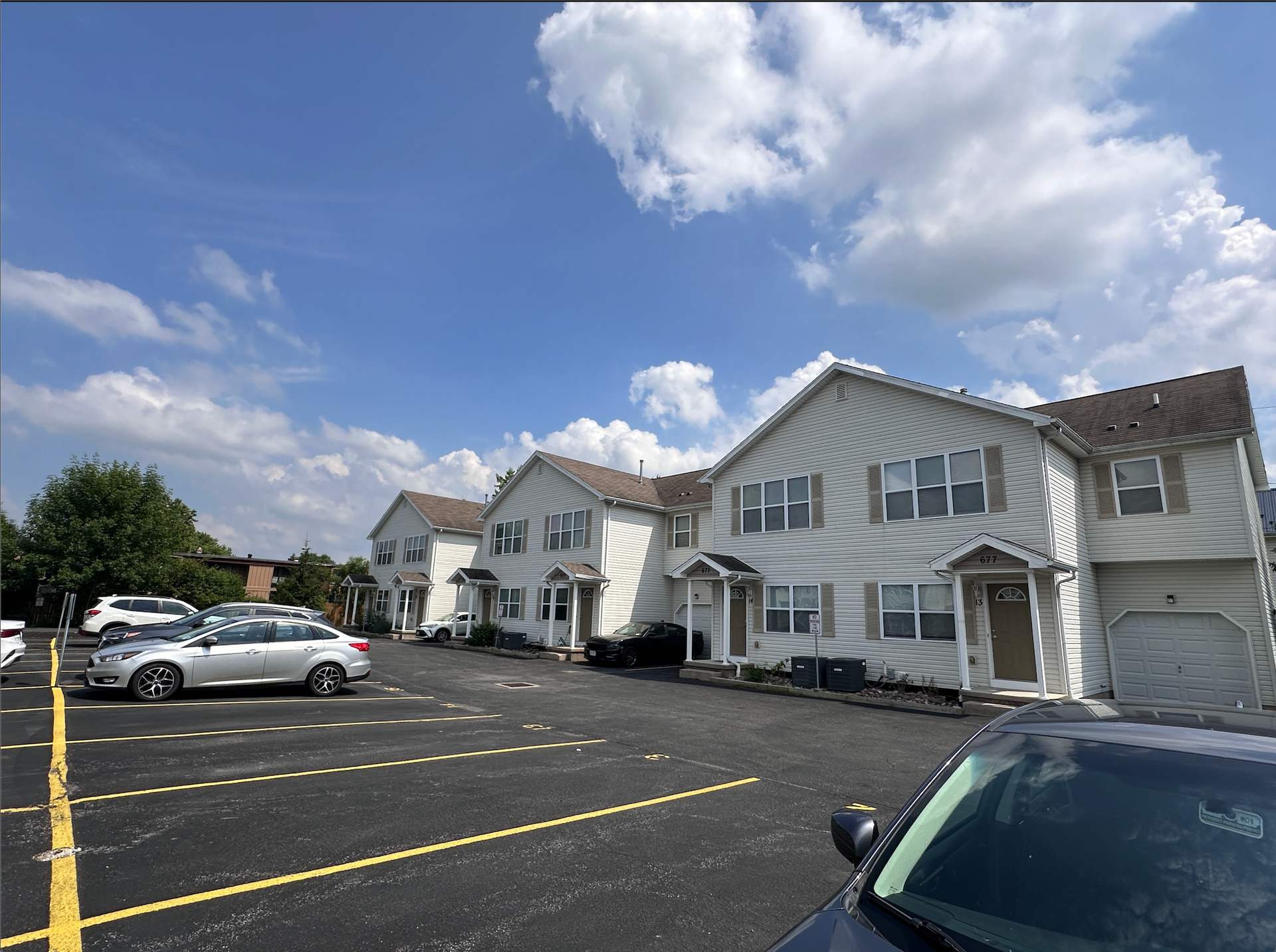A row of houses with cars parked in front of them