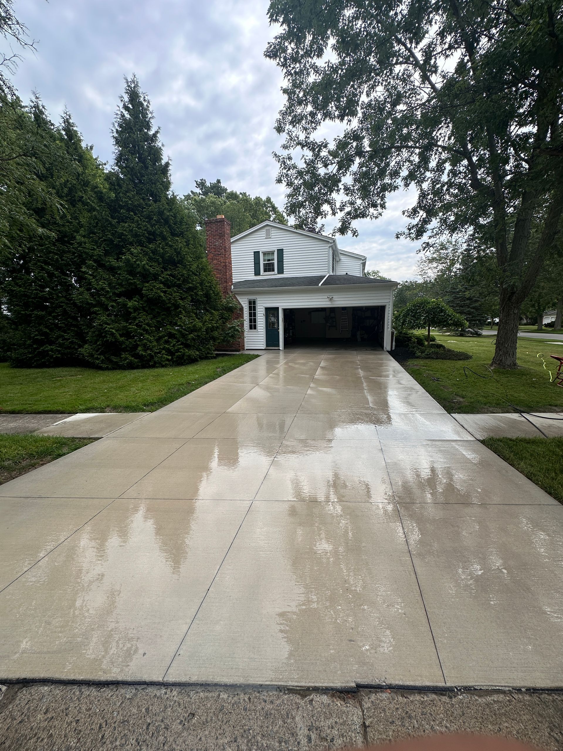 A concrete driveway leading to a white house with a garage.