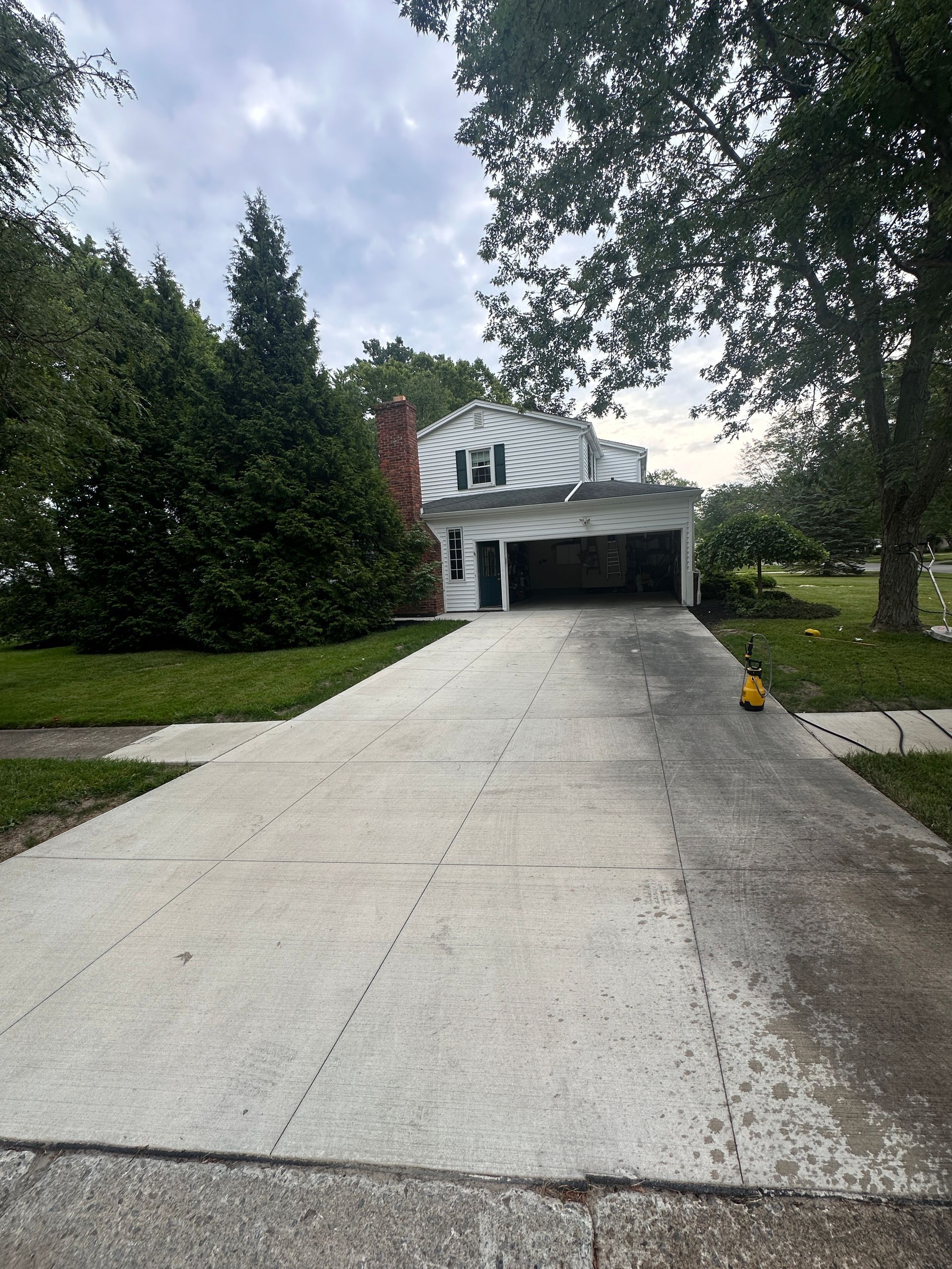 A concrete driveway leading to a house with a garage.