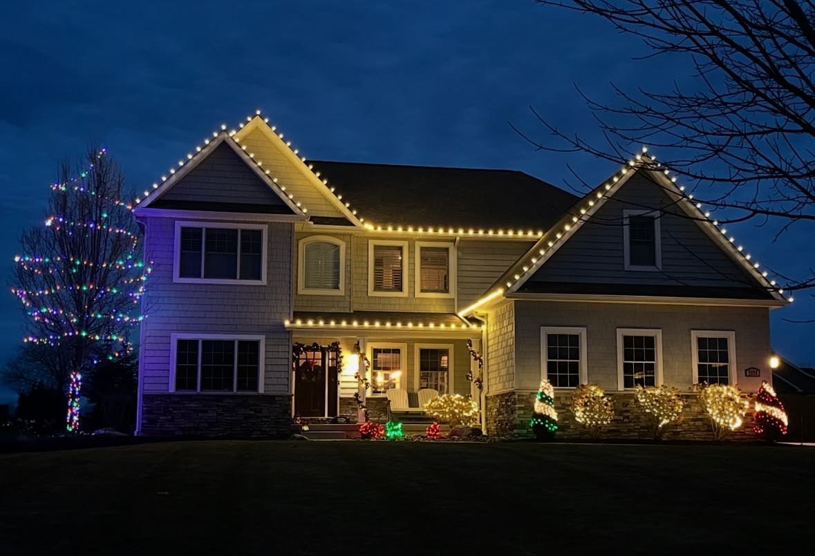 A large house is decorated with christmas lights at night.