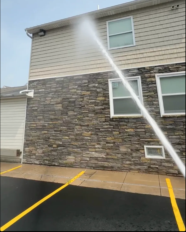 A hose is spraying water on the side of a building.