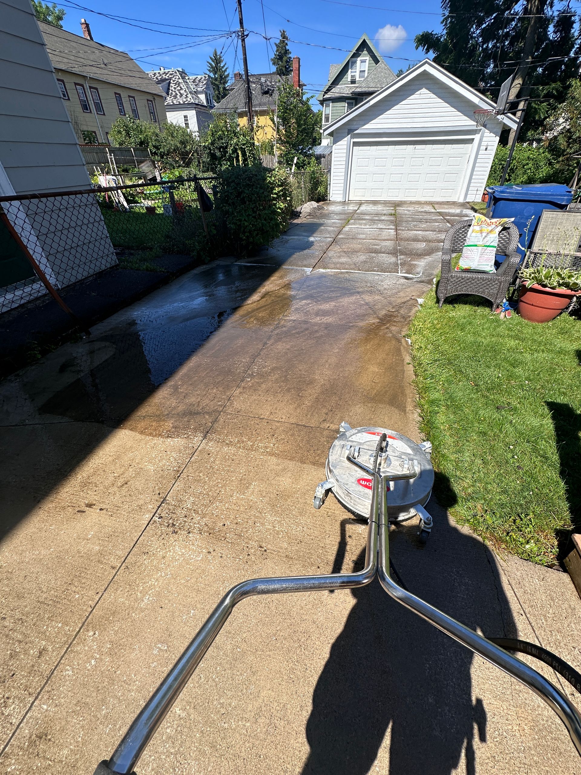 A shadow of a person is cast on the sidewalk in front of a garage.