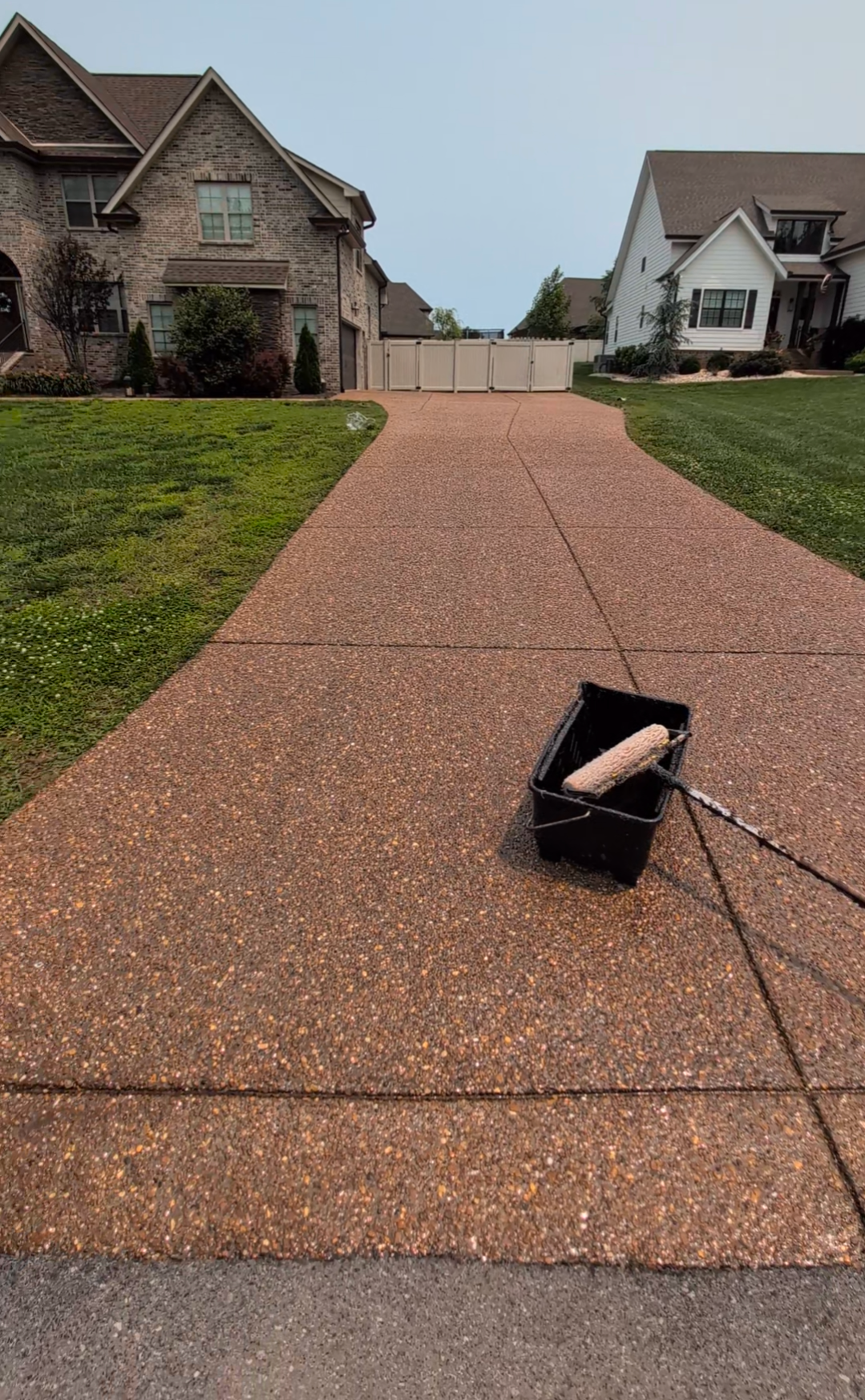 A concrete driveway is being painted in front of a house.