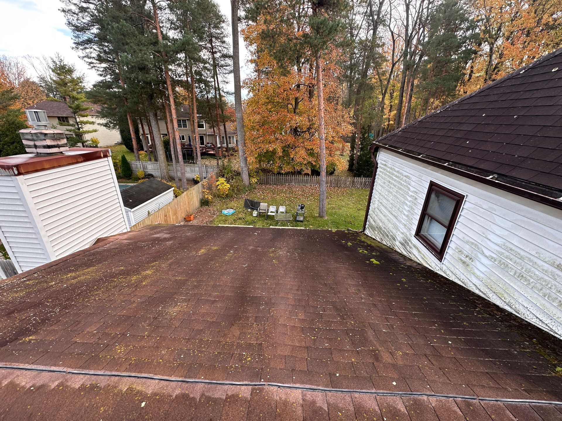 A house with a roof that is covered in dirt and trees in the background.
