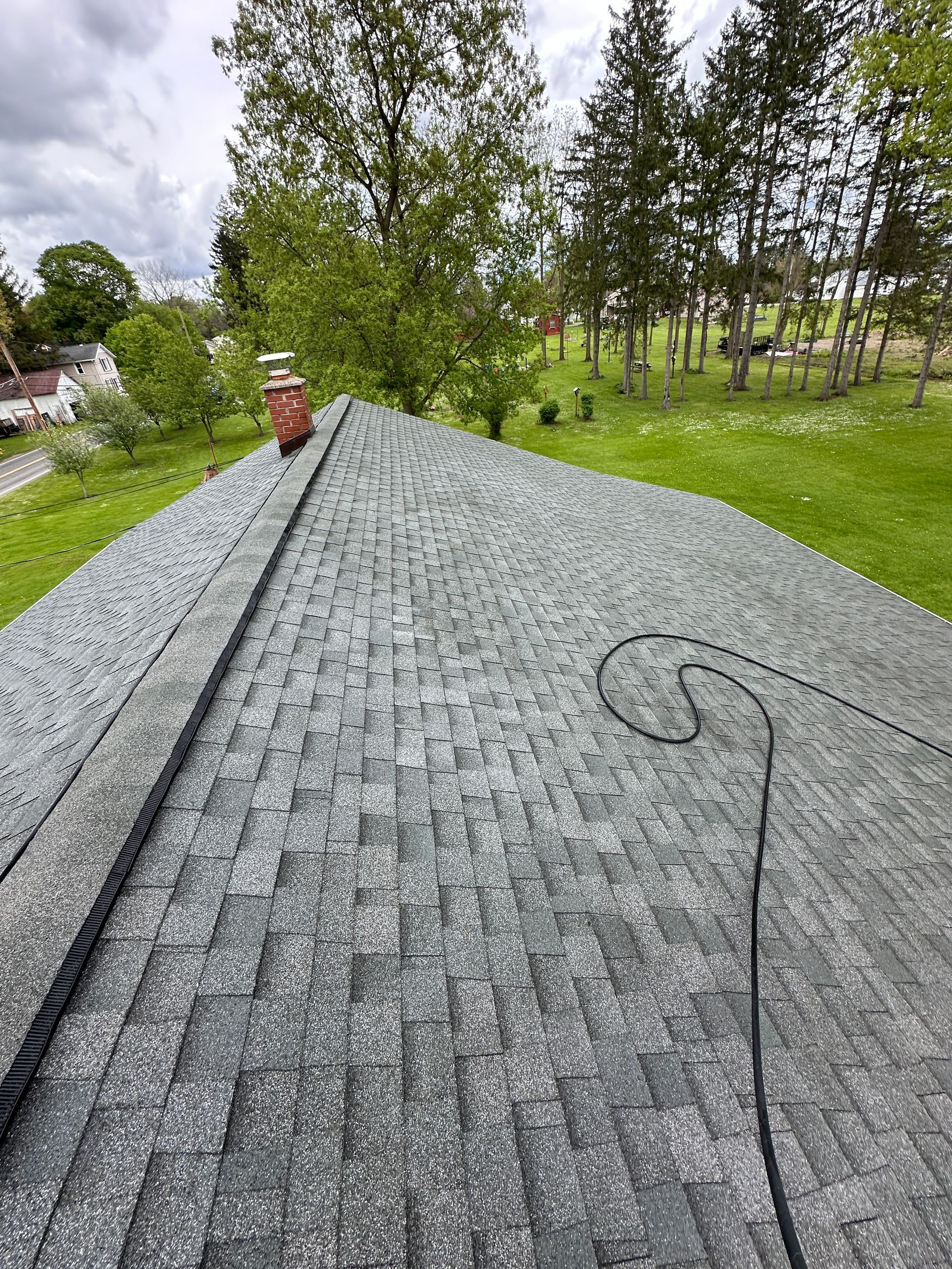 A roof with a chimney on it and trees in the background.