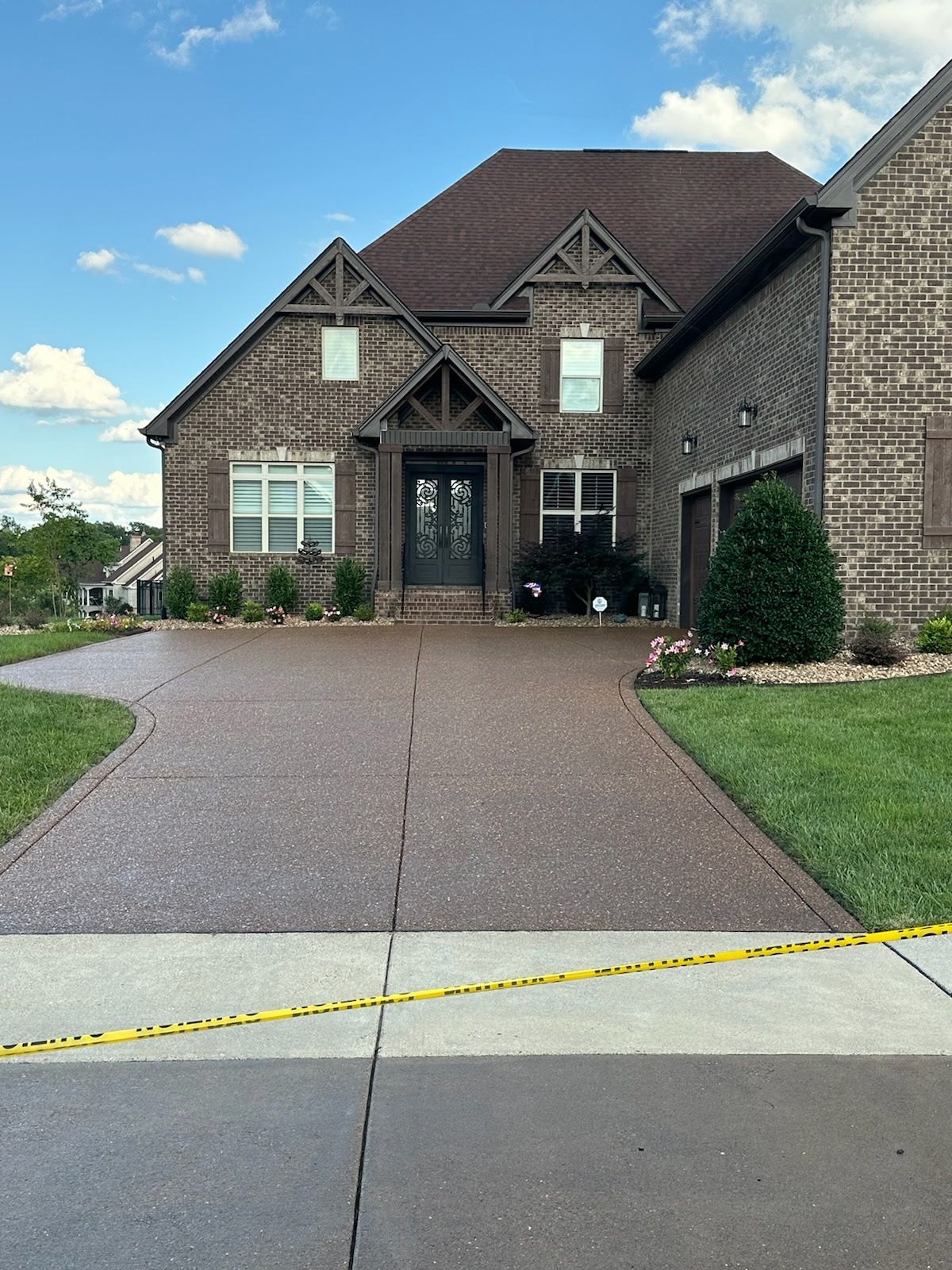 A large brick house with a concrete driveway in front of it.