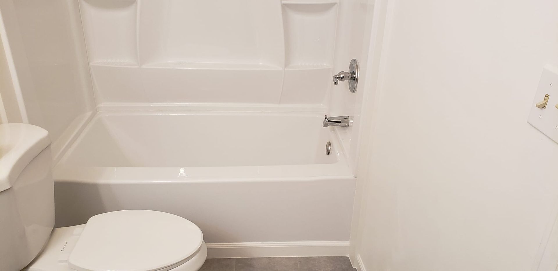 A bathroom with a toilet , bathtub and shower.