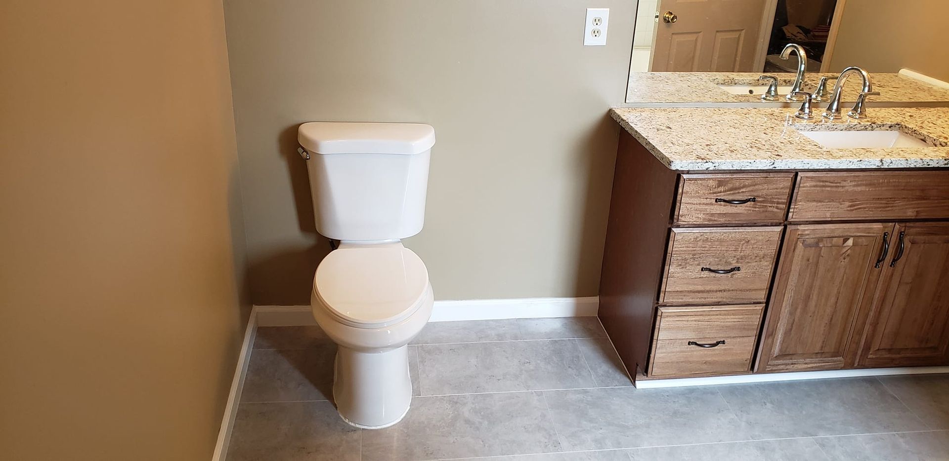 A bathroom with a toilet , sink and mirror.