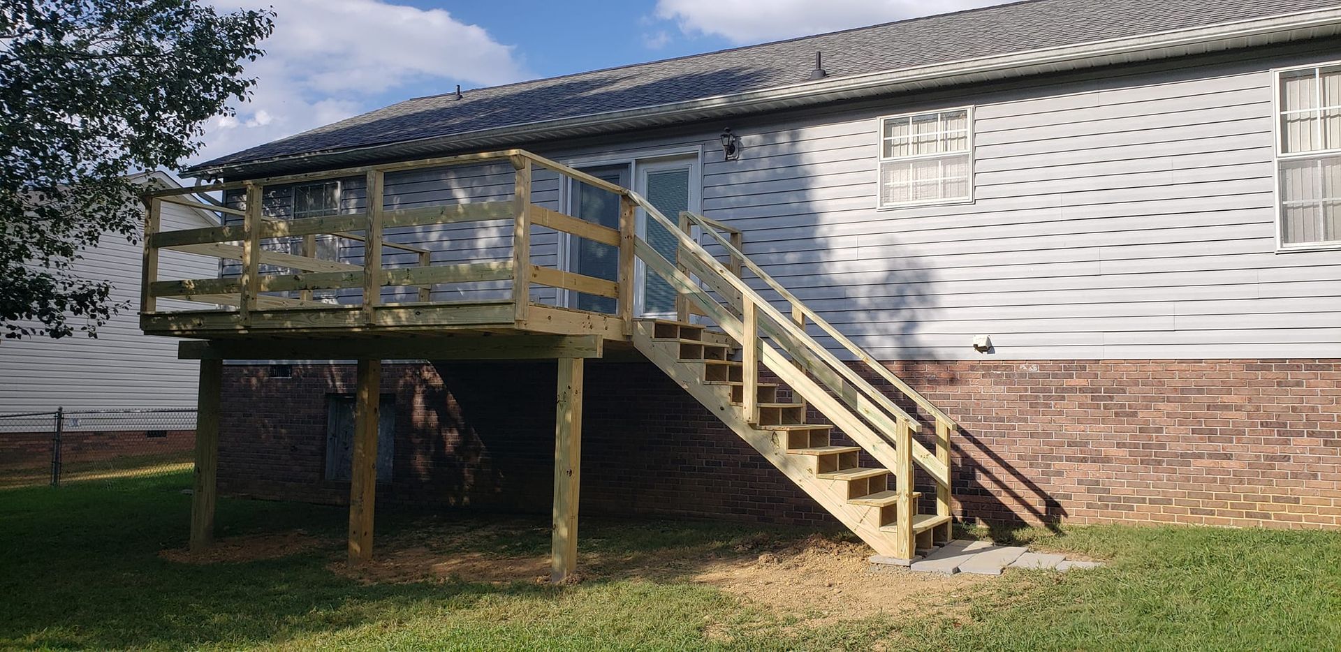 A house with a wooden deck and stairs leading up to it.