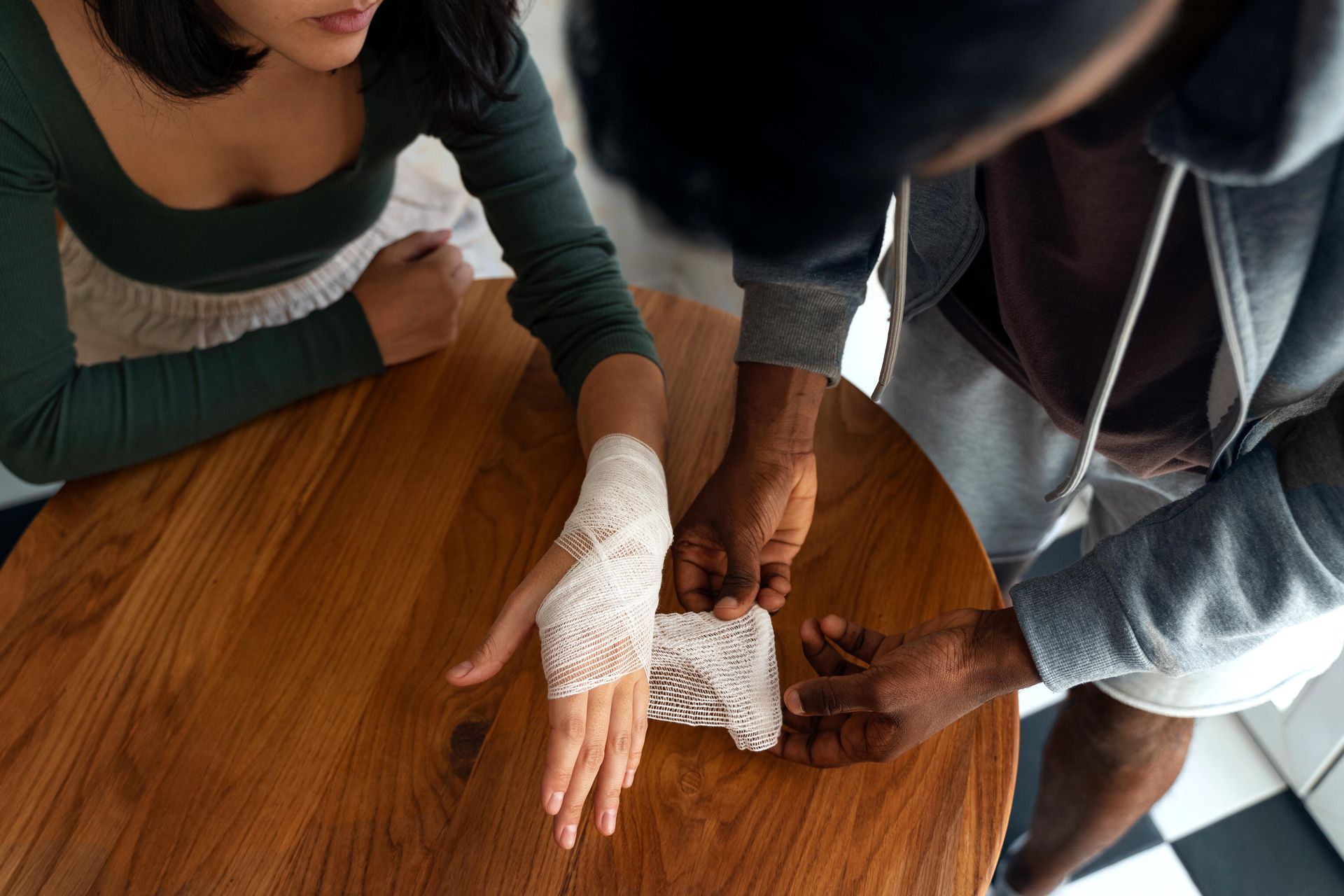 A man is putting a bandage on a woman 's hand.