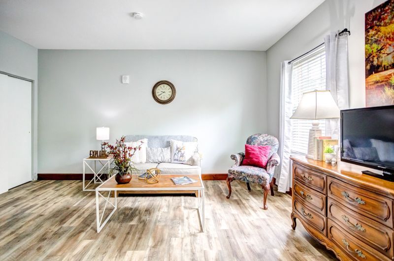 A living room with a couch , chair , coffee table and television.