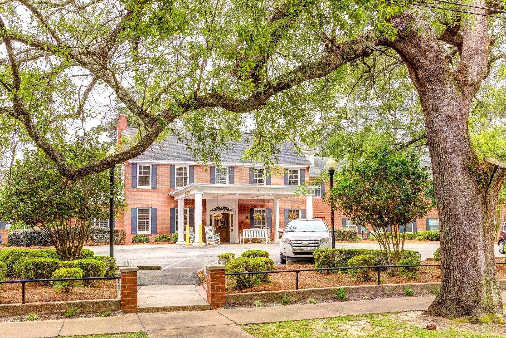 A large brick house with a car parked in front of it.