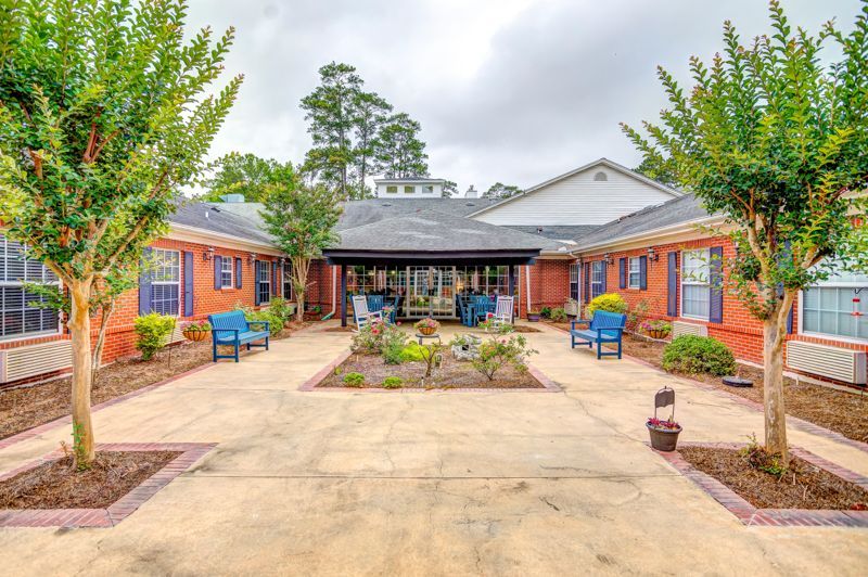A courtyard with benches and trees in front of a brick building.