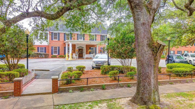 A brick building with a car parked in front of it and a tree in front of it.