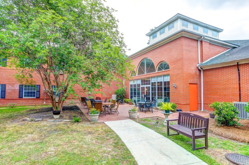 A brick building with a patio area and a bench in front of it.