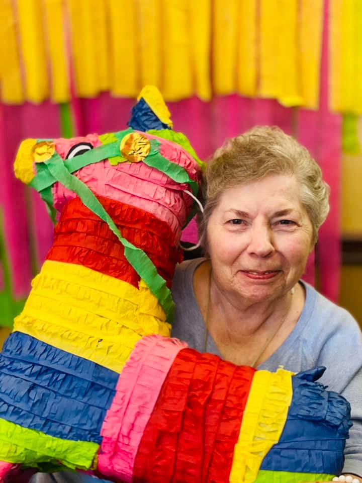 A woman is holding a colorful piñata in her hands.