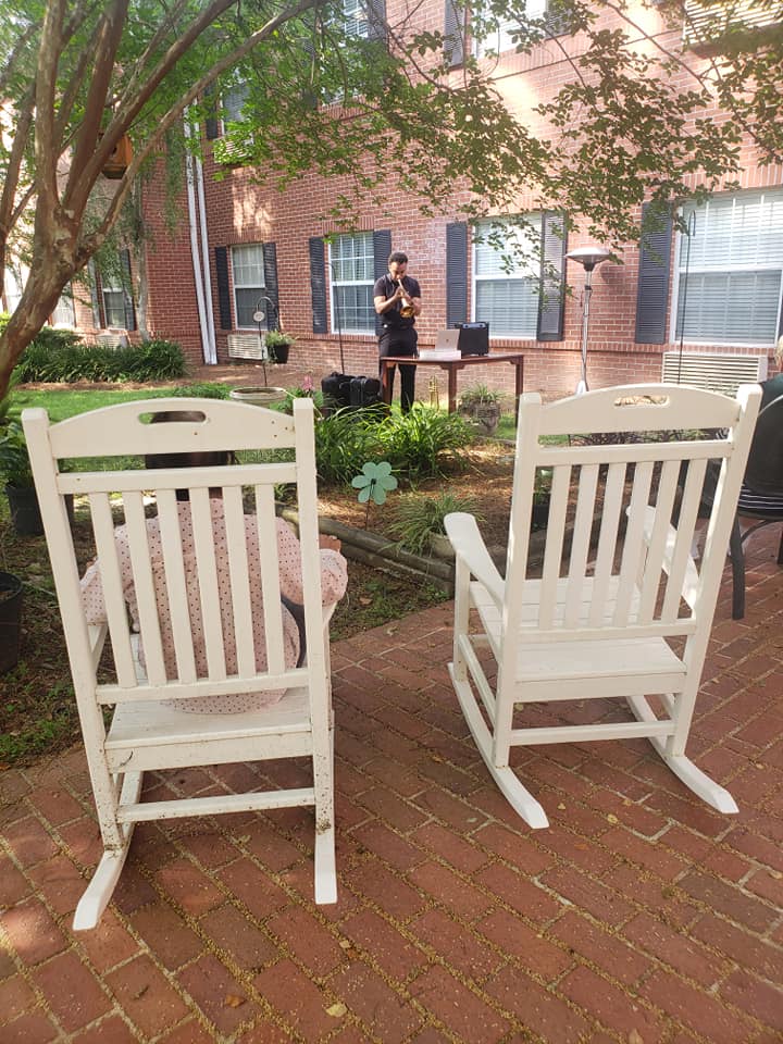 Two white rocking chairs are sitting on a brick patio in front of a brick building.