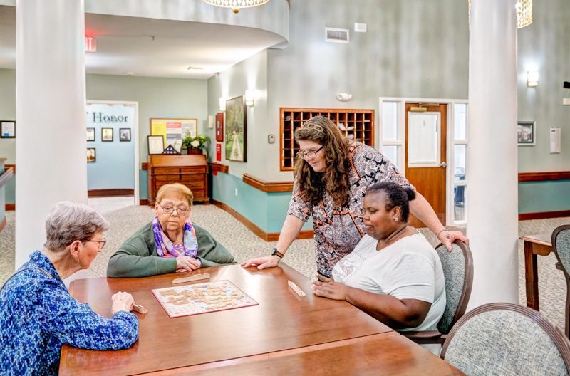 A group of elderly women are sitting around a table playing a game.