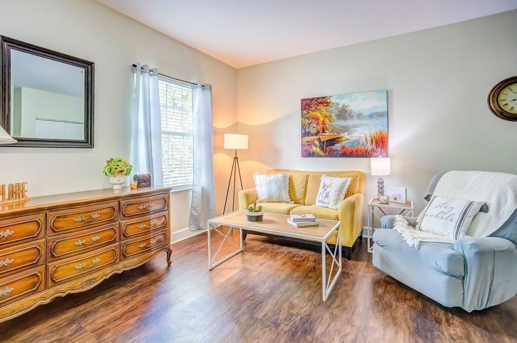 A living room with a couch , chair , coffee table and dresser.