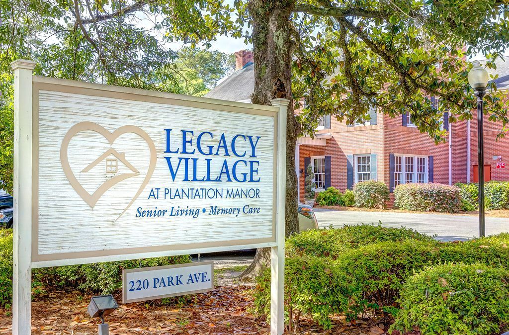 A sign for legacy village is sitting in front of a brick building.