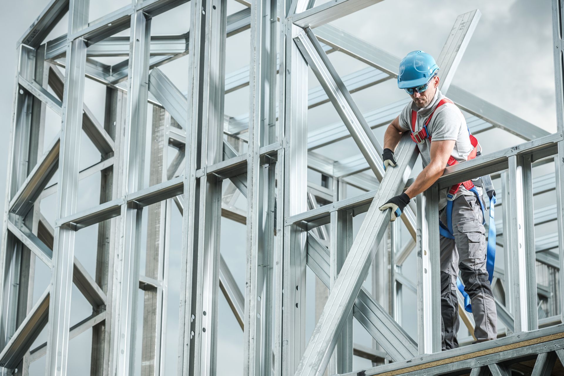Construction worker in a hard hat assembling steel frame of a building.