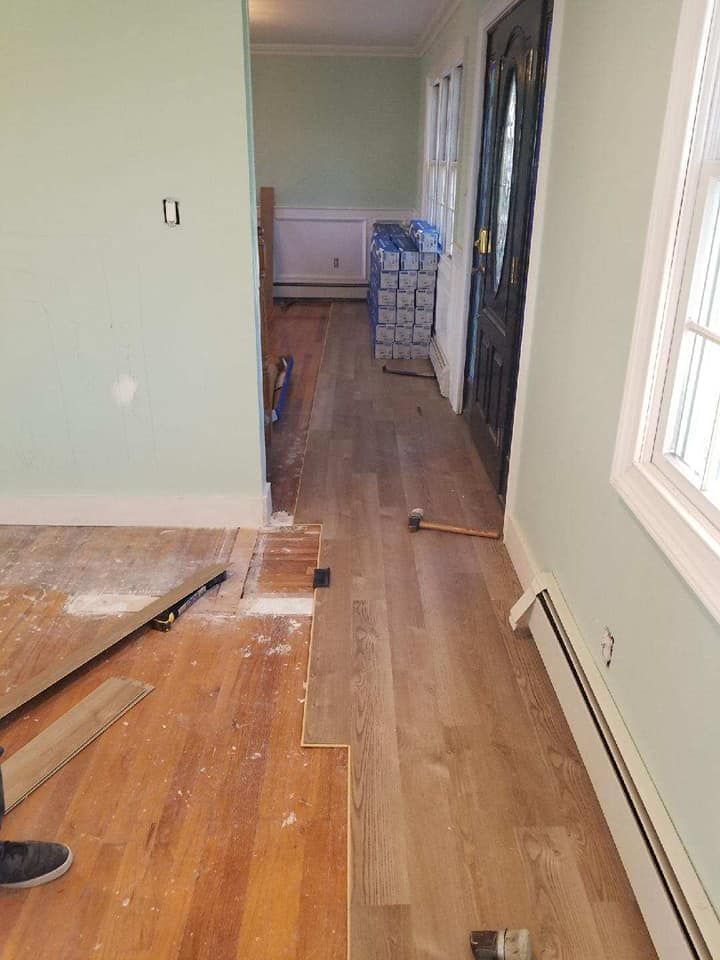 A person is laying wooden flooring in a hallway.