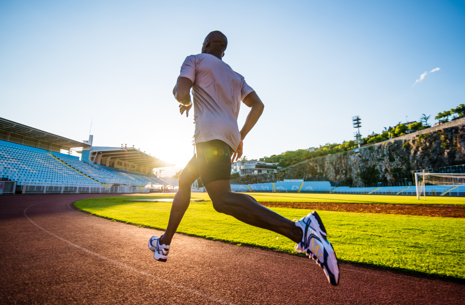 A man is running on a track in a stadium.