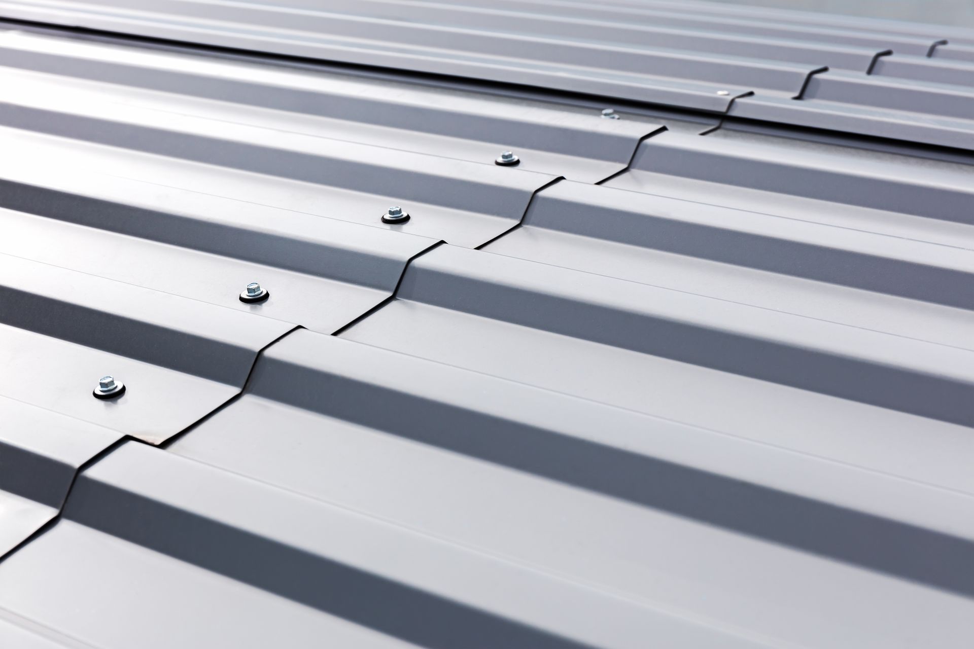 Silver corrugated metal roof with rows of screws and overlapping seams Silver corrugated metal roof with rows of screws and overlapping seams