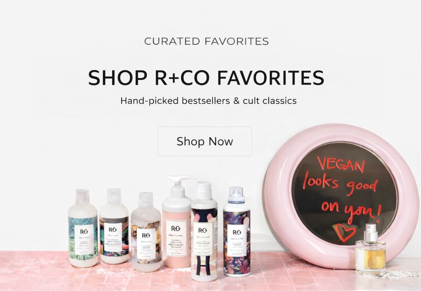Advertisement for R+Co hair products. Featuring several bottles, pink mirror, and a