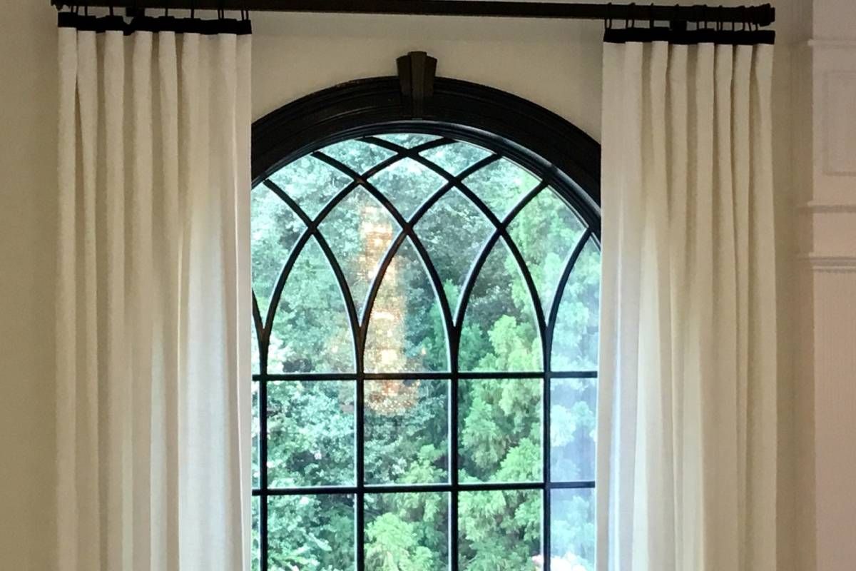 A tall arched window with drapery window treatments at Upstate Window Fashions near Greenville, Sout