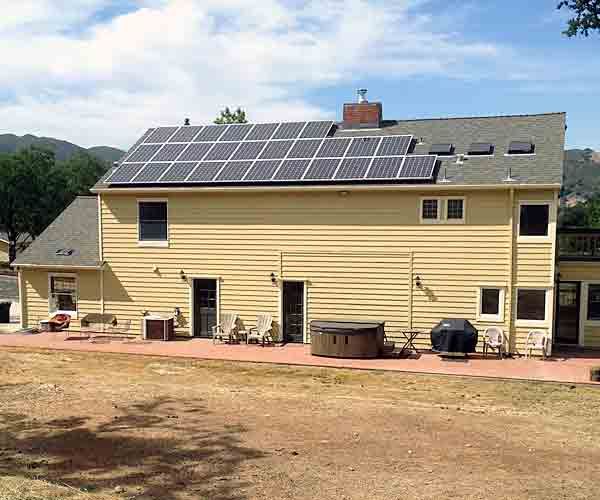 A large yellow house with solar panels on the roof.