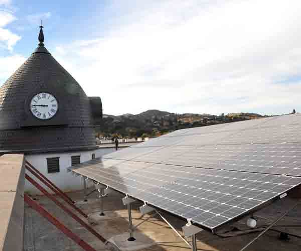 A clock on top of a building with solar panels in front of it