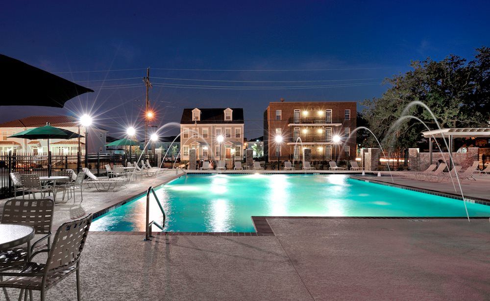 A large swimming pool is lit up at night in front of a building.