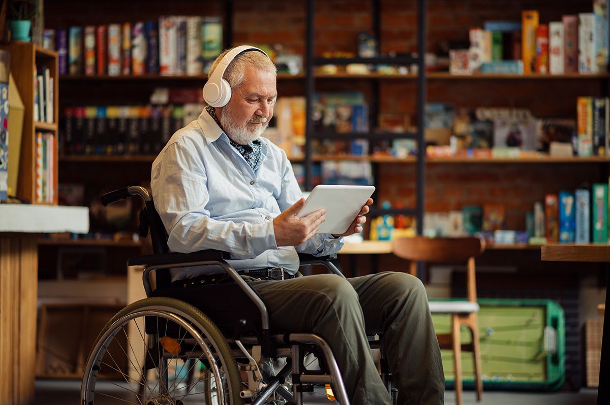 Disabled man using tablet with headphones