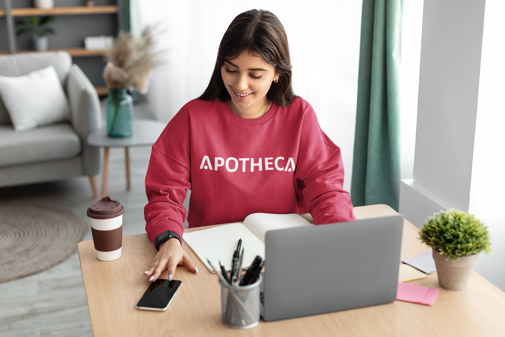 A woman is sitting at a desk with a laptop and a book.