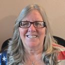 A woman wearing glasses and an american flag shirt is smiling.