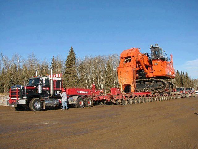 Plant Relocation Movers — Long Red Truck Carrying an Orange Truck in Monroe, NC