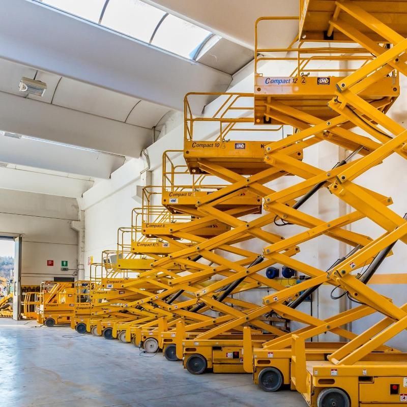 Piattaforme aeree gialle allineate in un magazzino.