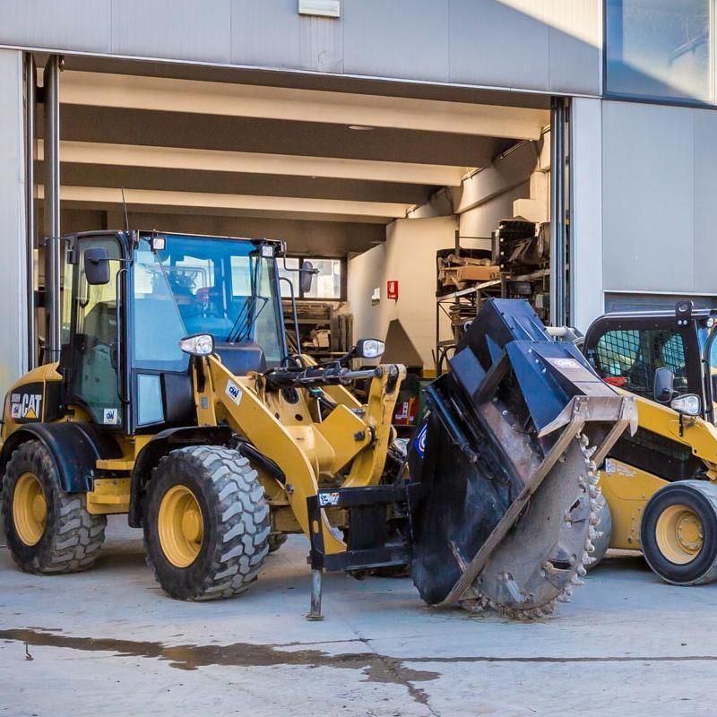 Caricatore da cantiere giallo con grande testa di taglio, un altro caricatore in un garage.