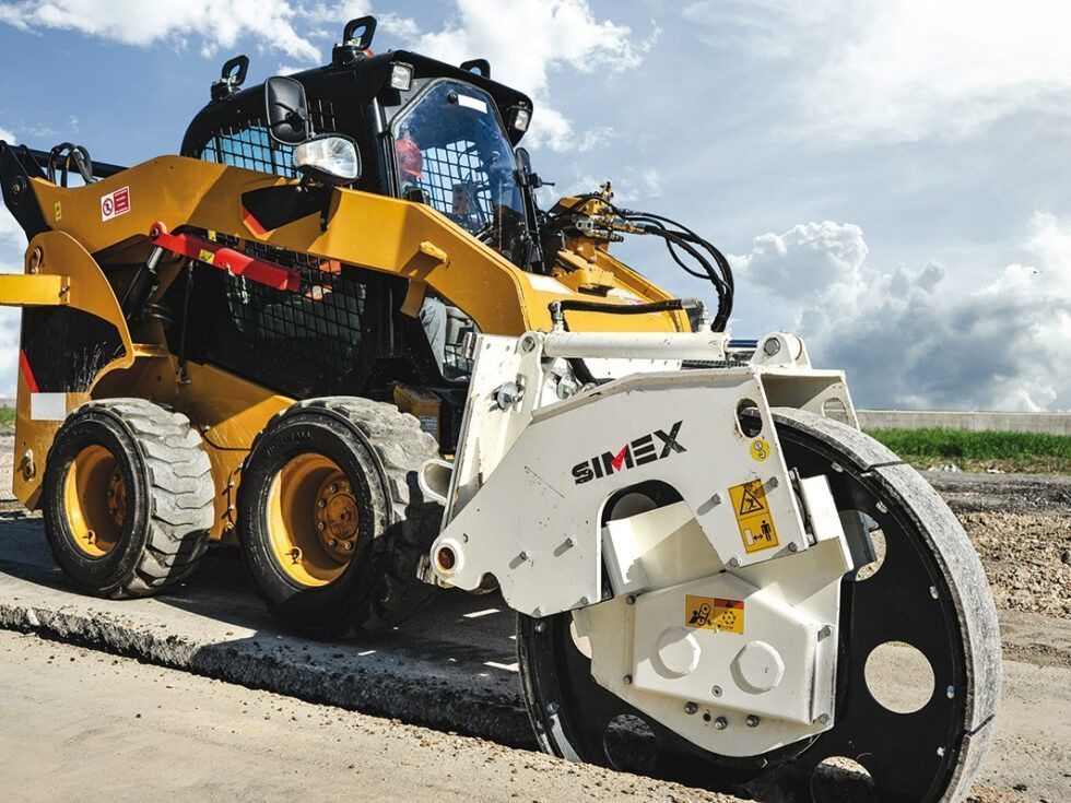 Minipala gialla con ruota fresante che leviga il manto stradale in una giornata di sole.