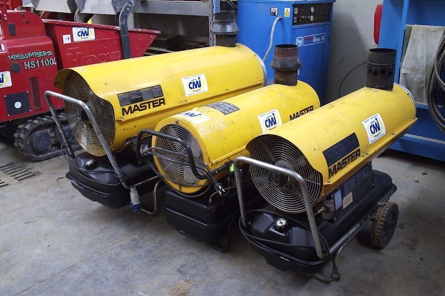 Tre riscaldatori portatili gialli del marchio Master con base e maniglie nere.
