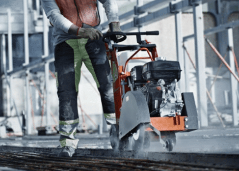 Operaio che taglia il cemento con una sega elettrica in un cantiere edile.
