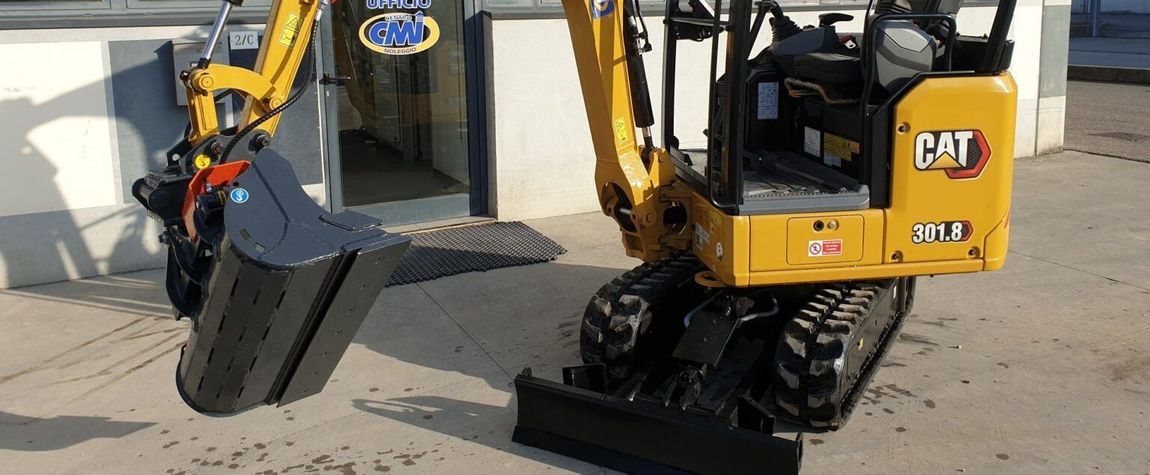 Miniescavatore Caterpillar giallo con benna e cingoli neri.