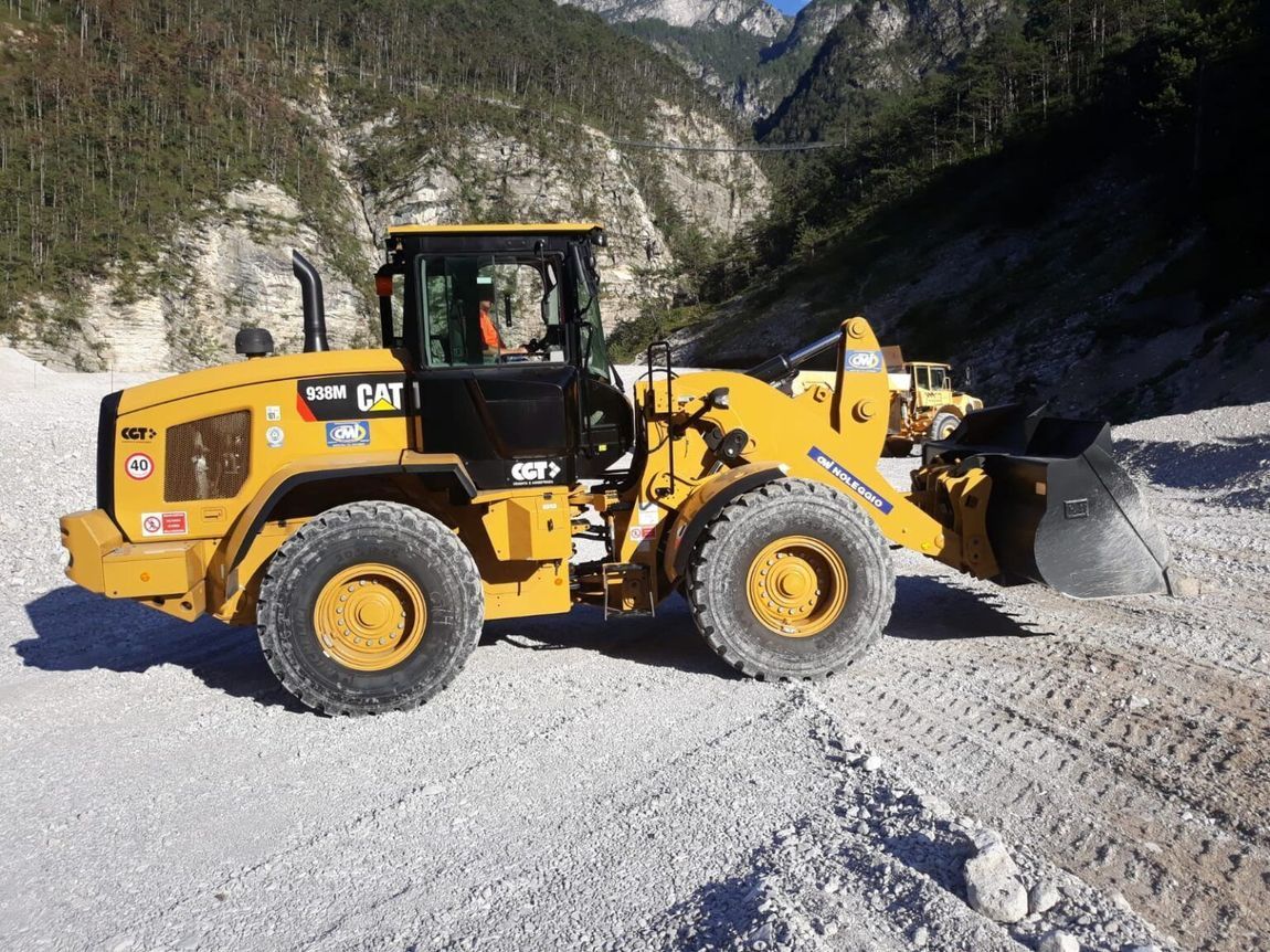 Pala gommata CAT gialla su ghiaia in un ambiente montuoso.