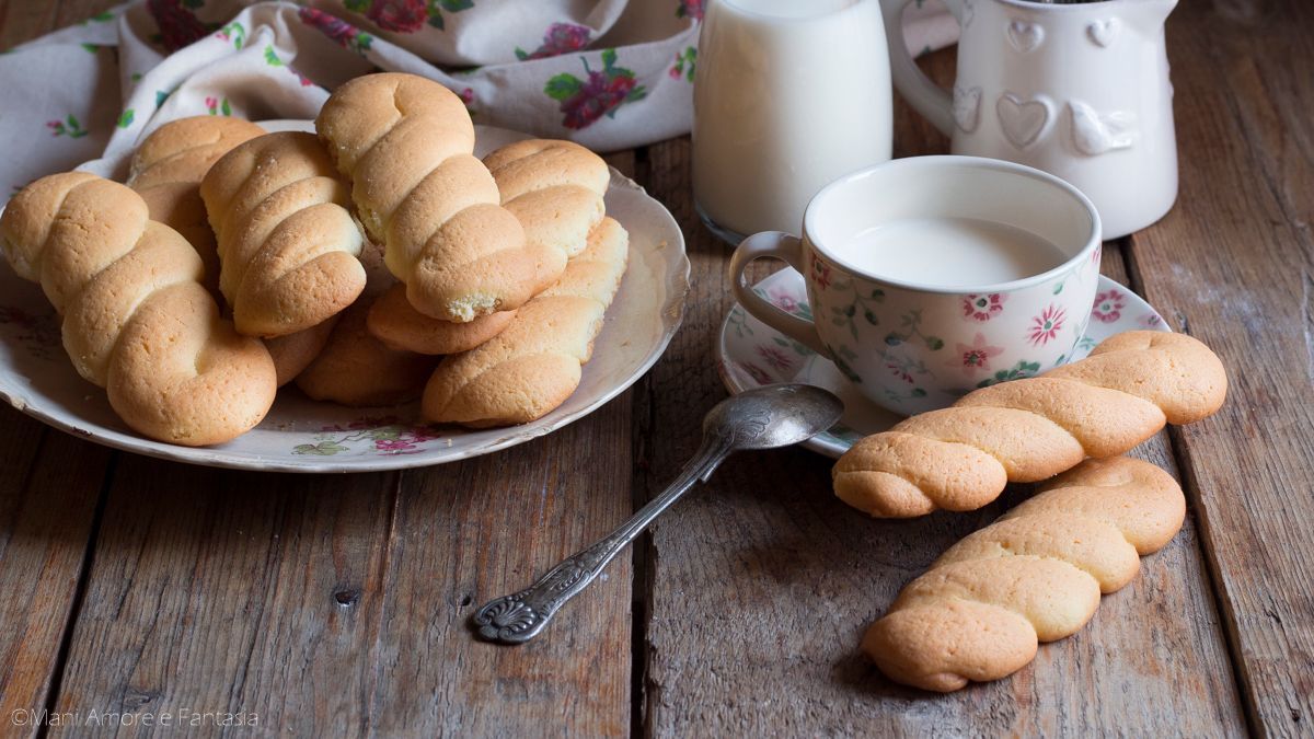 Vassoio di pasticcini assortiti, alcuni spolverati con zucchero a velo, in un vassoio rivestito di carta stagnola dorata.