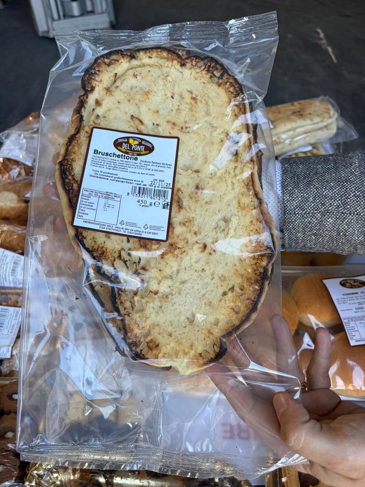 Mano che tiene un sacchetto di plastica sigillato con all'interno una grande fetta di pane tostato.