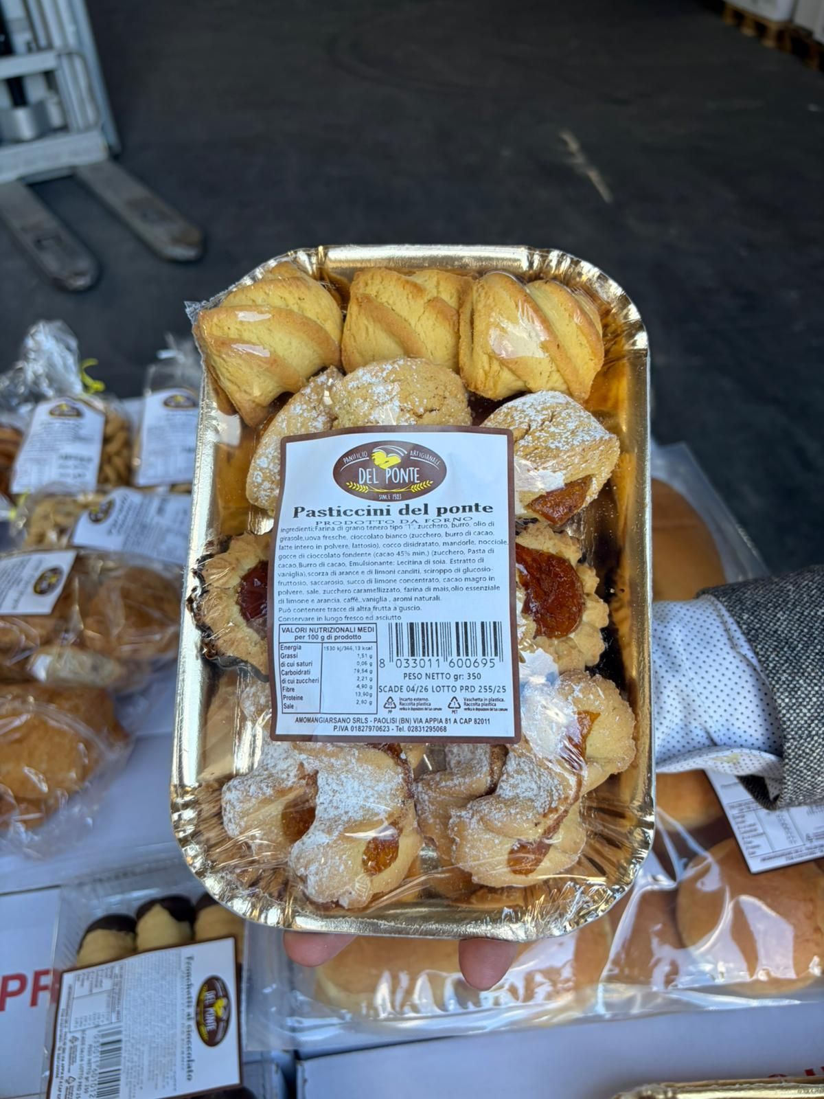 Vassoio di pasticcini assortiti, alcuni spolverati con zucchero a velo, in un vassoio rivestito di carta stagnola dorata.