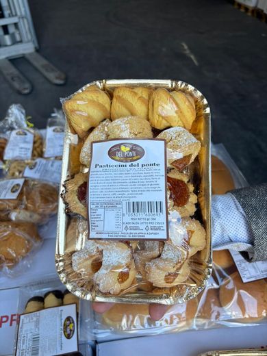 Vassoio di pasticcini assortiti, alcuni spolverati con zucchero a velo, in un vassoio rivestito di carta stagnola dorata.